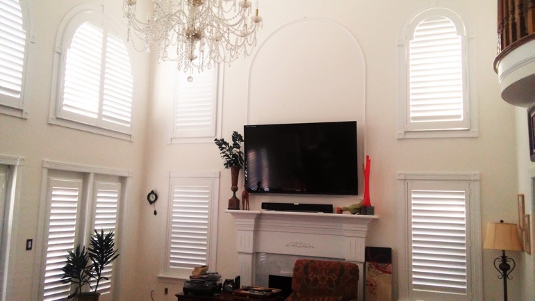 Destin great room with wall-mounted TV and arc windows.